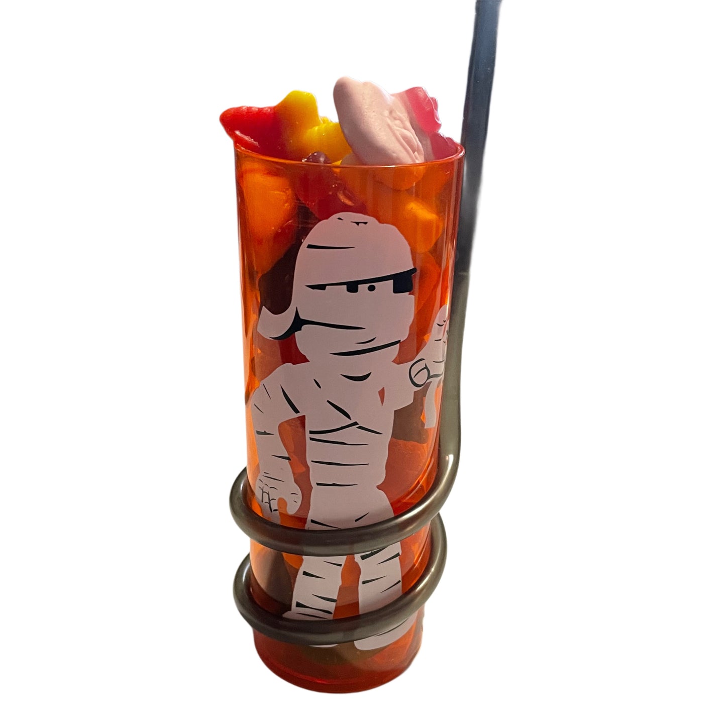 Tall orange cup with a cartoon mummy design and attached straw, filled with gummy halloween sweets, on a white background.